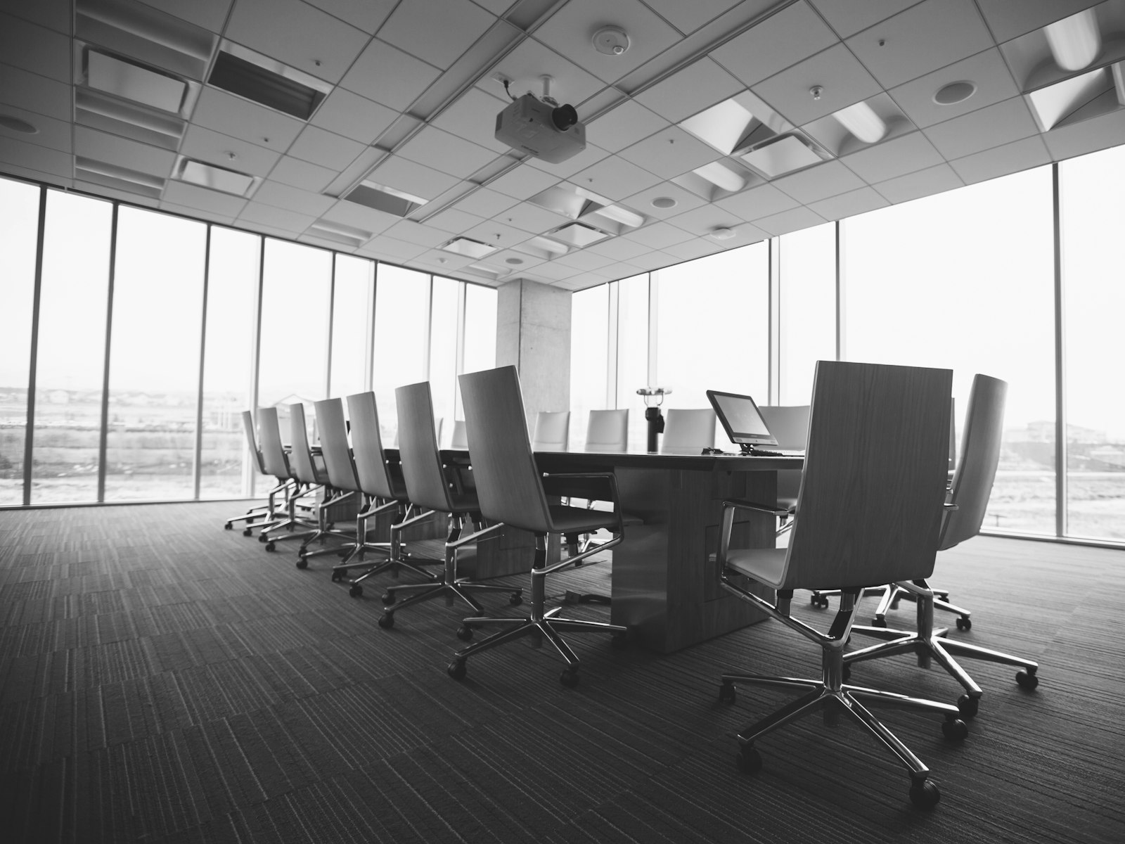 An empty boardroom with a long table and chairs, in black and white