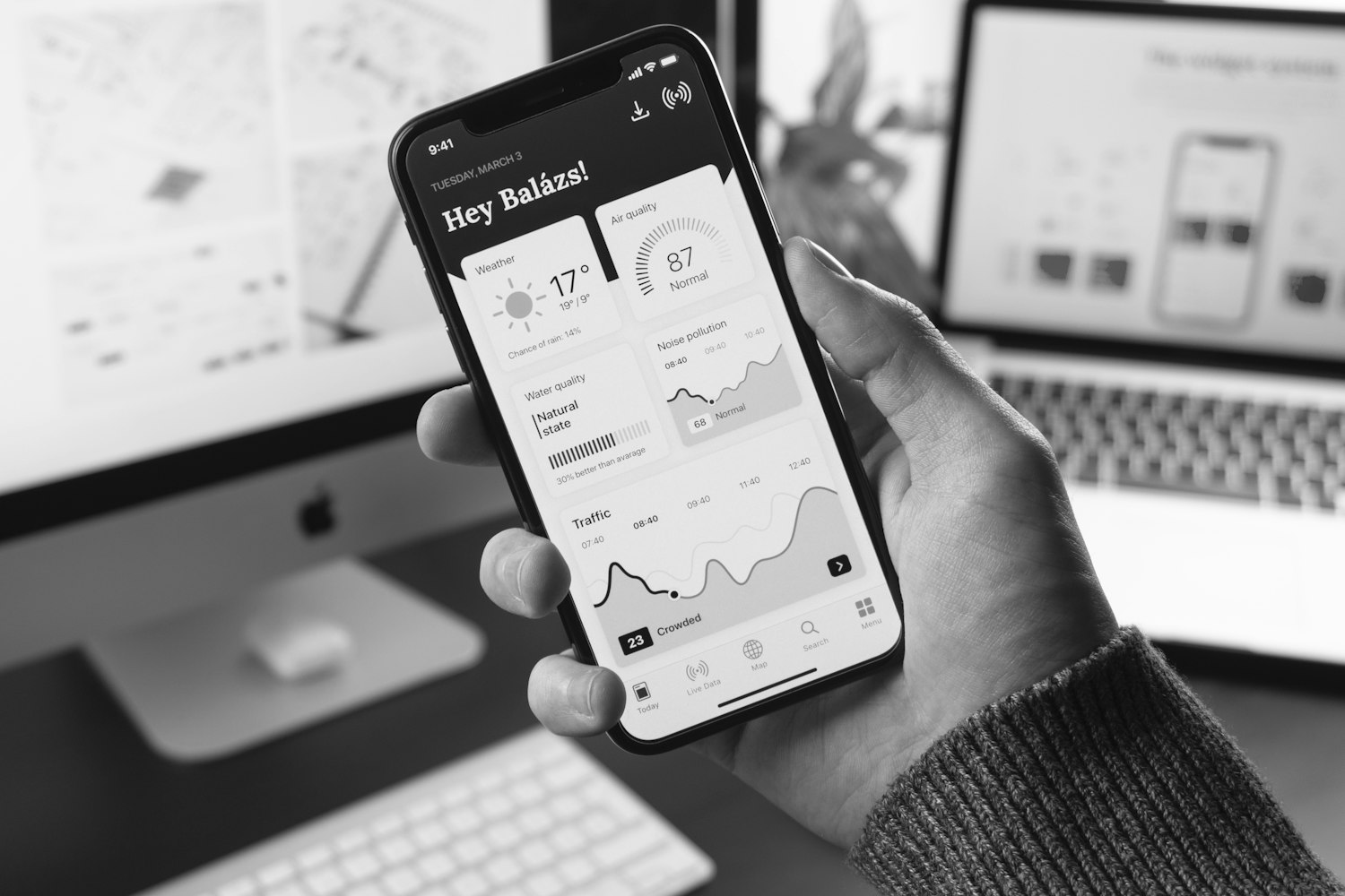 A hand holding a phone that shows a dashboard, in black and white