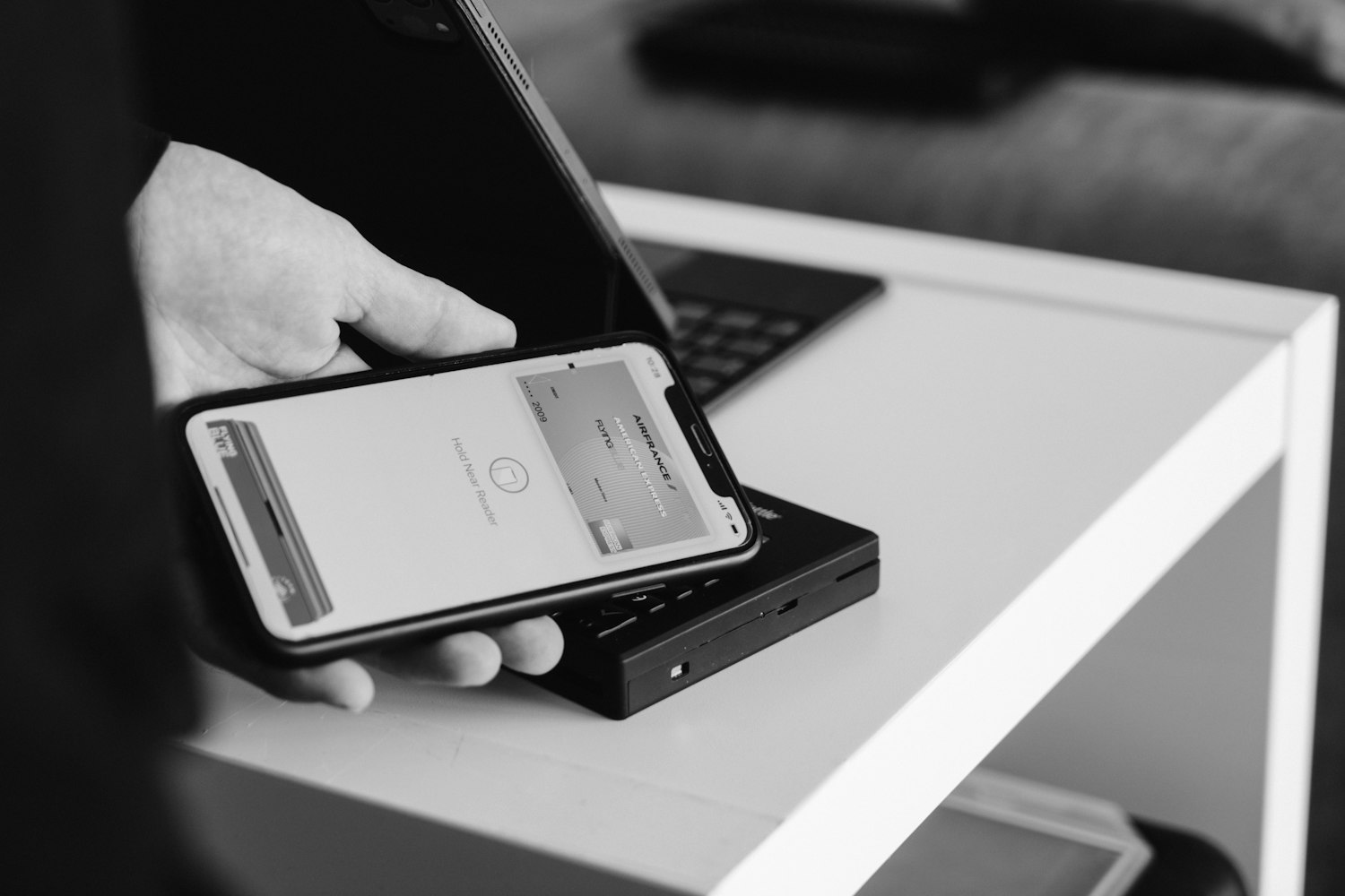 A phone held over a card reader, in black and white